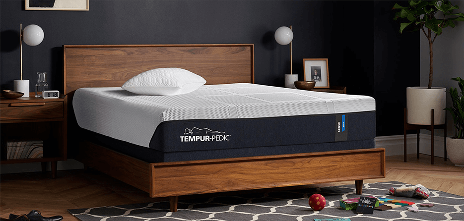 Image of mattress on wood bed frame in room with black walls 